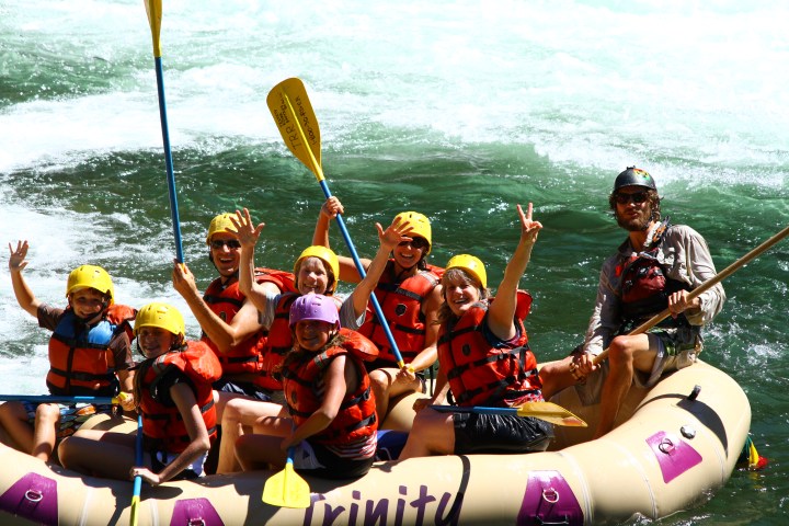 A happy group of adventurers poses while rafting on the Trinity River