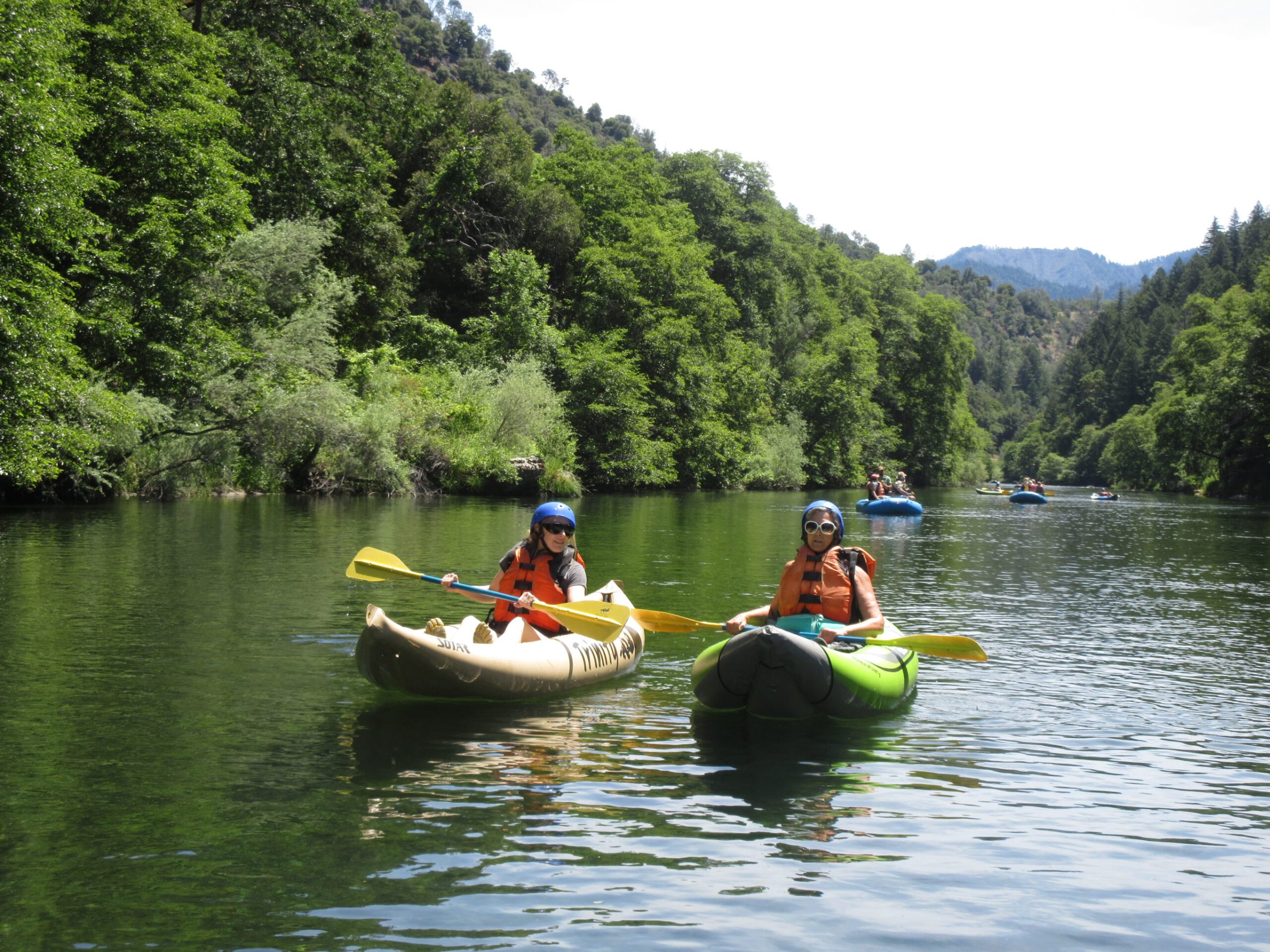 a man riding on the back of a boat next to a lake